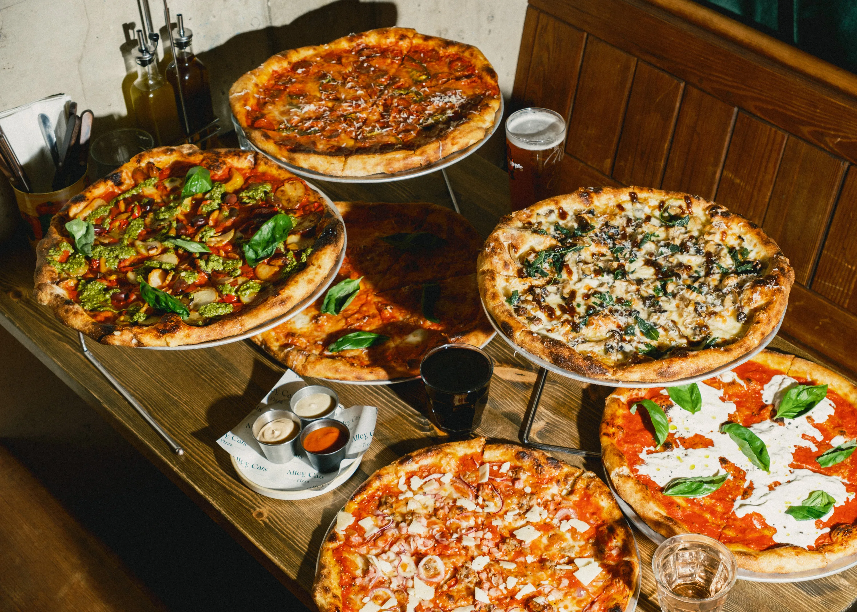 Alley Cats Pizza showcasing a variety of specialty pizzas on a communal table.