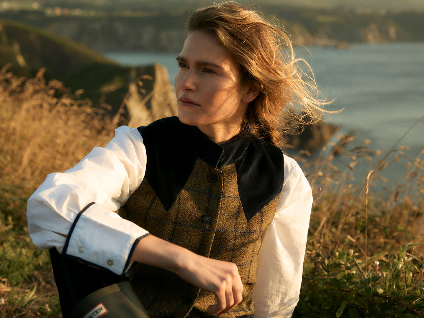 Model in BYAN clothing on a coastal cliff, evoking the brand's upcoming collection.