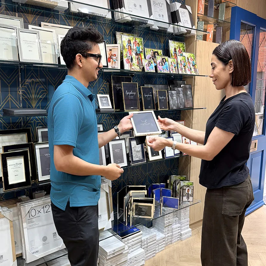 Customer and store assistant selecting a picture frame during an in-store framing consultation.