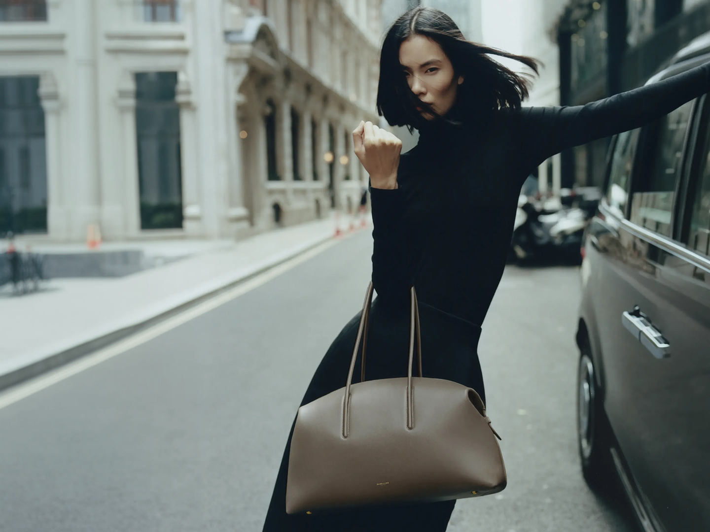 Model showcasing DeMellier handbag on a city street