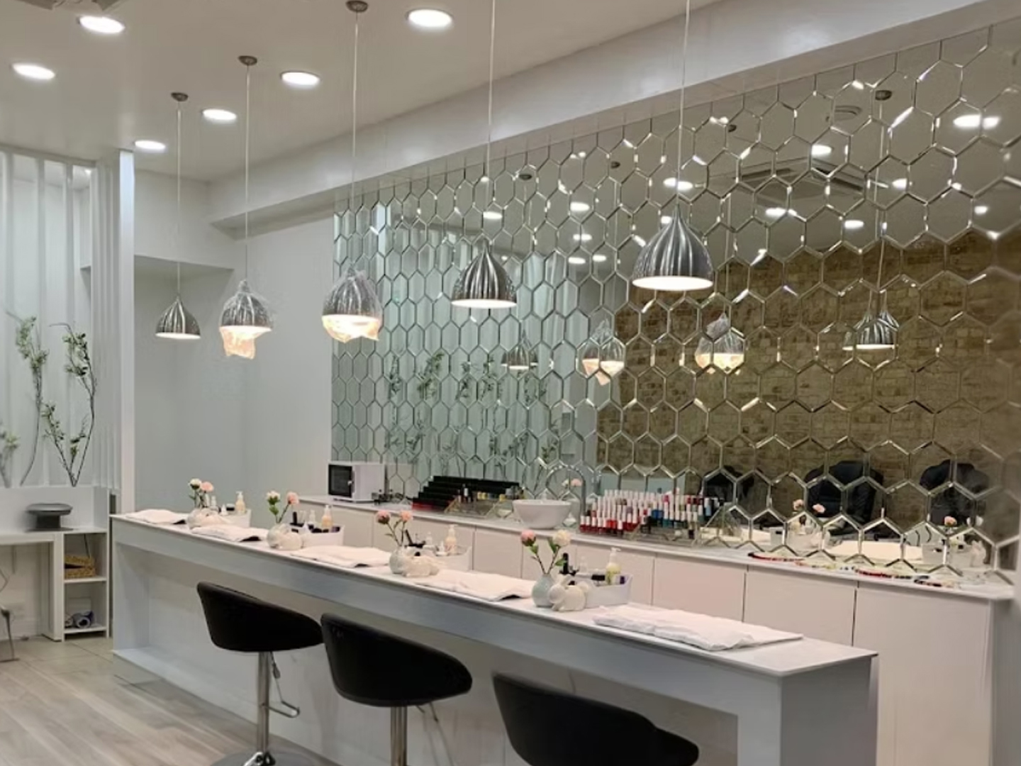Manicure bar with multiple workstations and seating in a modern nail and beauty salon.