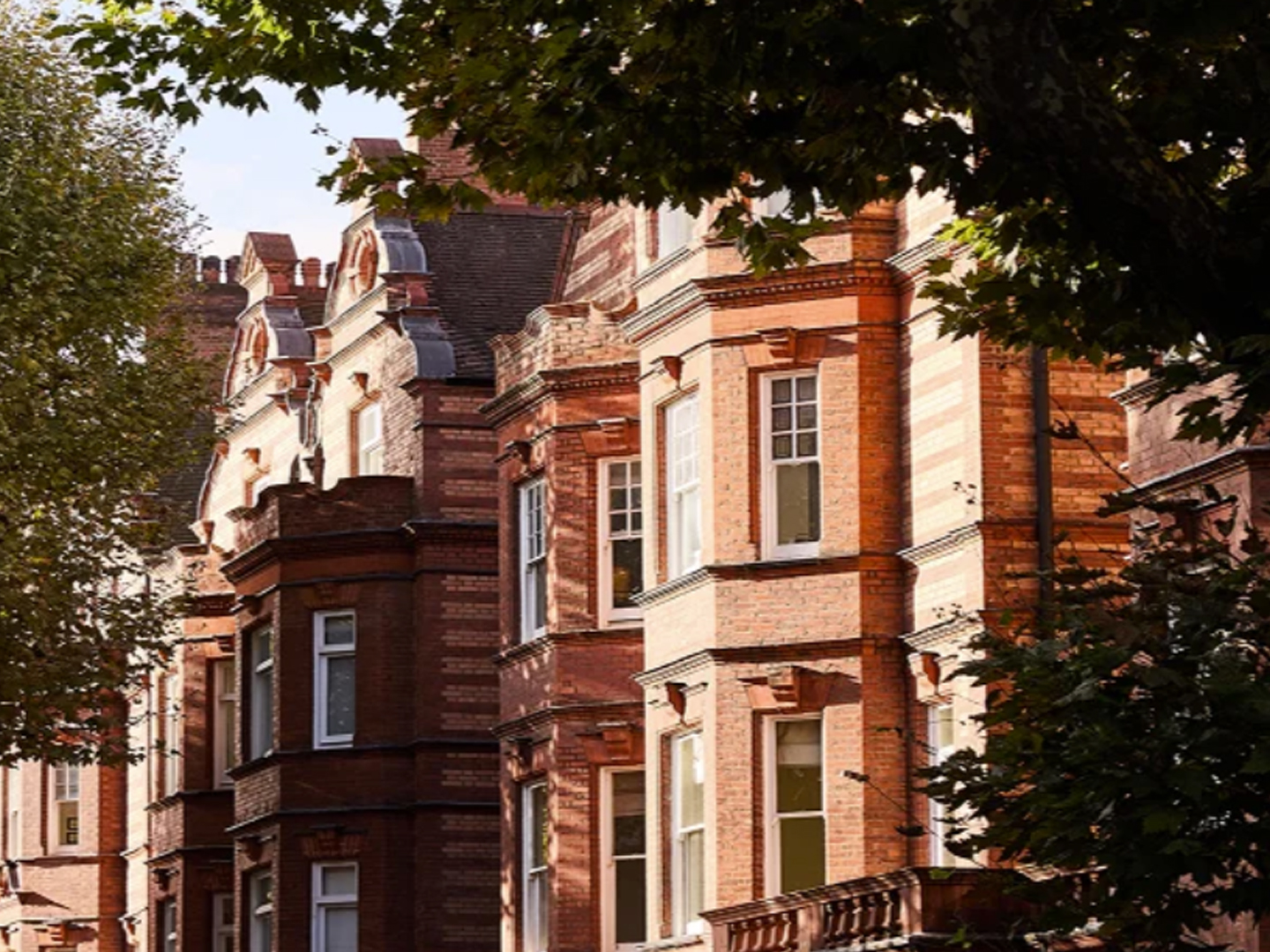 Victorian red-brick townhouses on a tree-lined London street