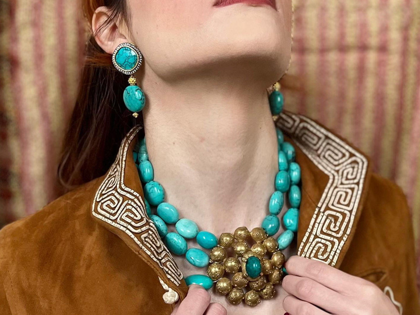Model showcasing statement turquoise jewelry and a decorative jacket collar.