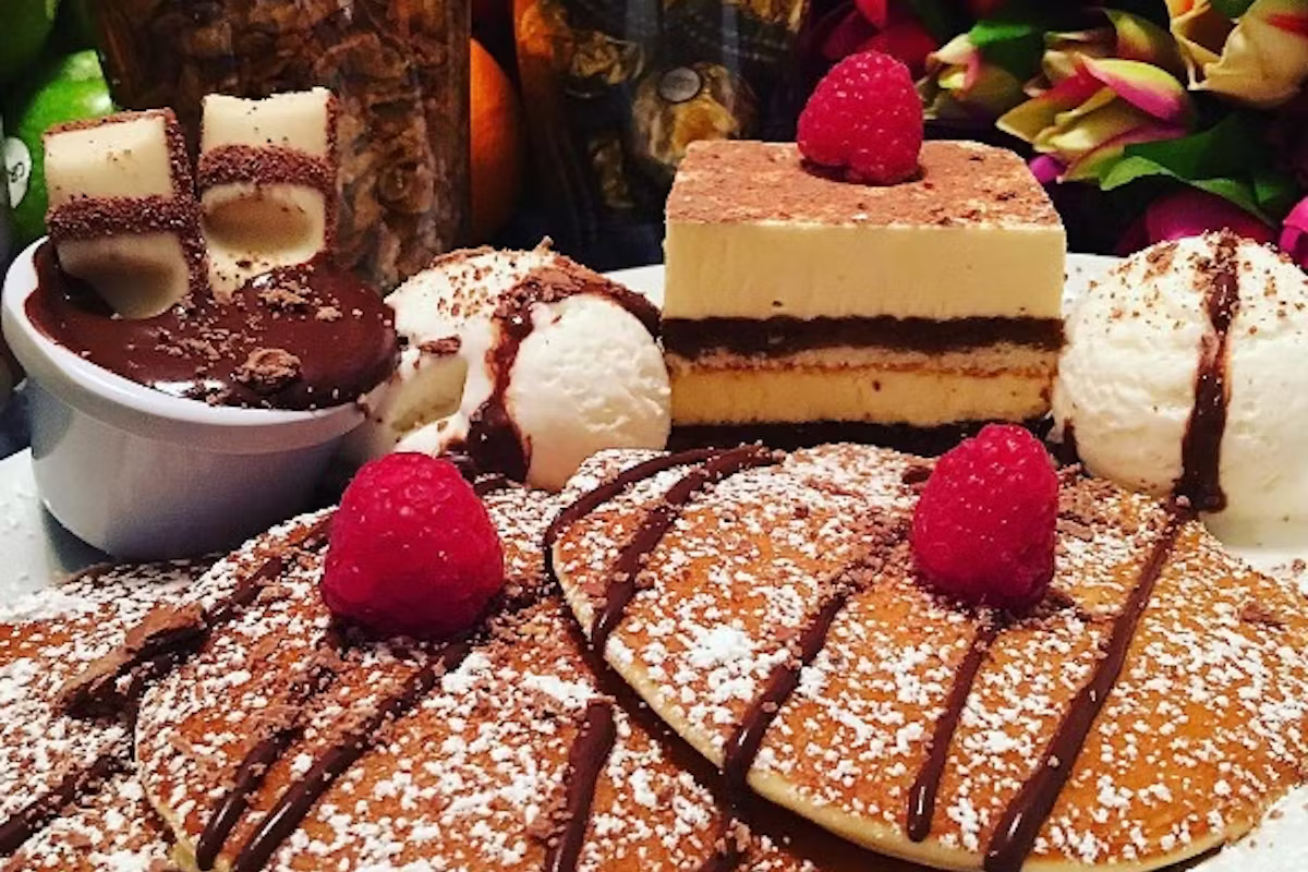 Dessert plate with pancakes, scoops of ice cream, chocolate sauce, and raspberries