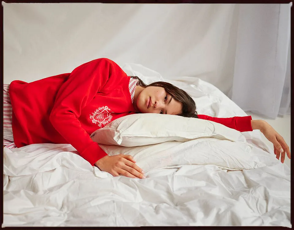 Young woman modeling a relaxed sweater while reclining on a bed