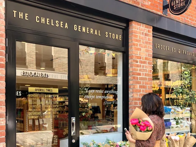Chelsea General Store storefront welcoming a customer carrying a bouquet