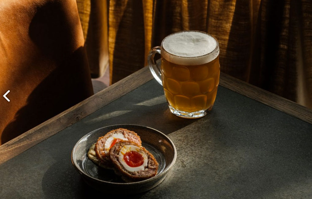 Pint of beer and a Scotch egg on a small plate as a pub snack