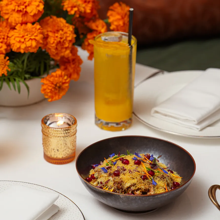 Diwali-inspired table setting with a festive bowl of garnished rice and a cocktail at Jumeirah Carlton Tower