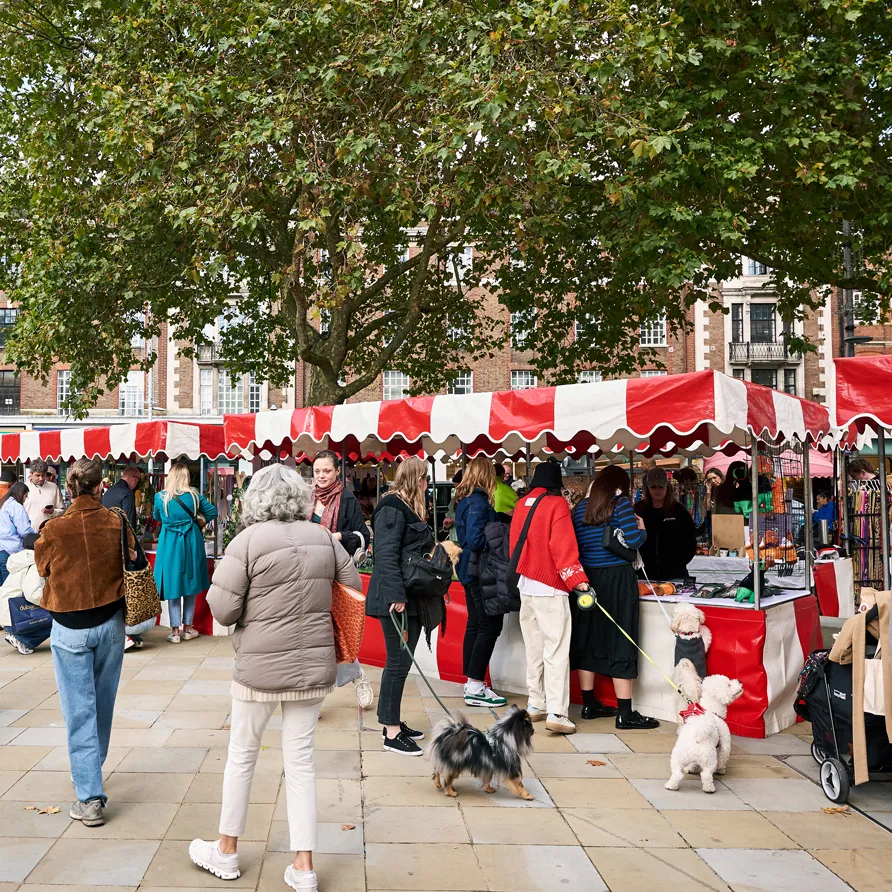 People and dogs socializing at a busy outdoor market during Chelsea Dog Day.