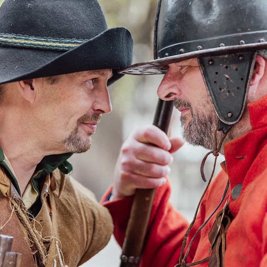 Historical reenactors face each other in a tense exchange at a history festival.