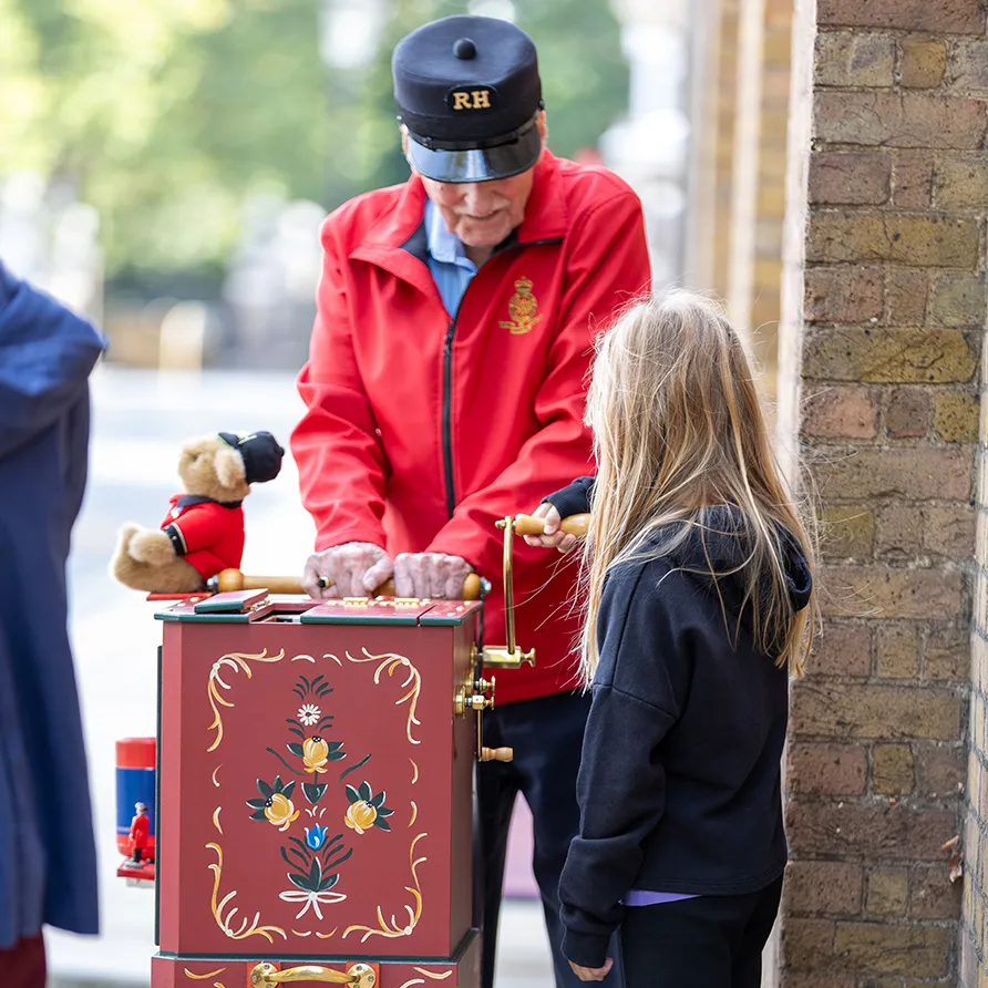 Street organist demonstrating a hand-cranked barrel organ to a young girl