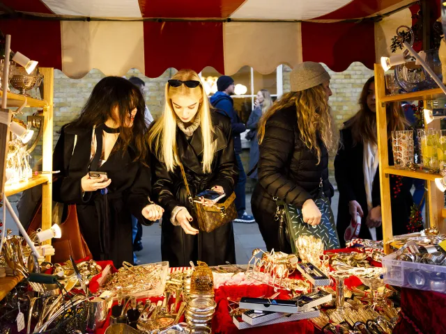 Shoppers browsing a Christmas market stall for holiday gifts