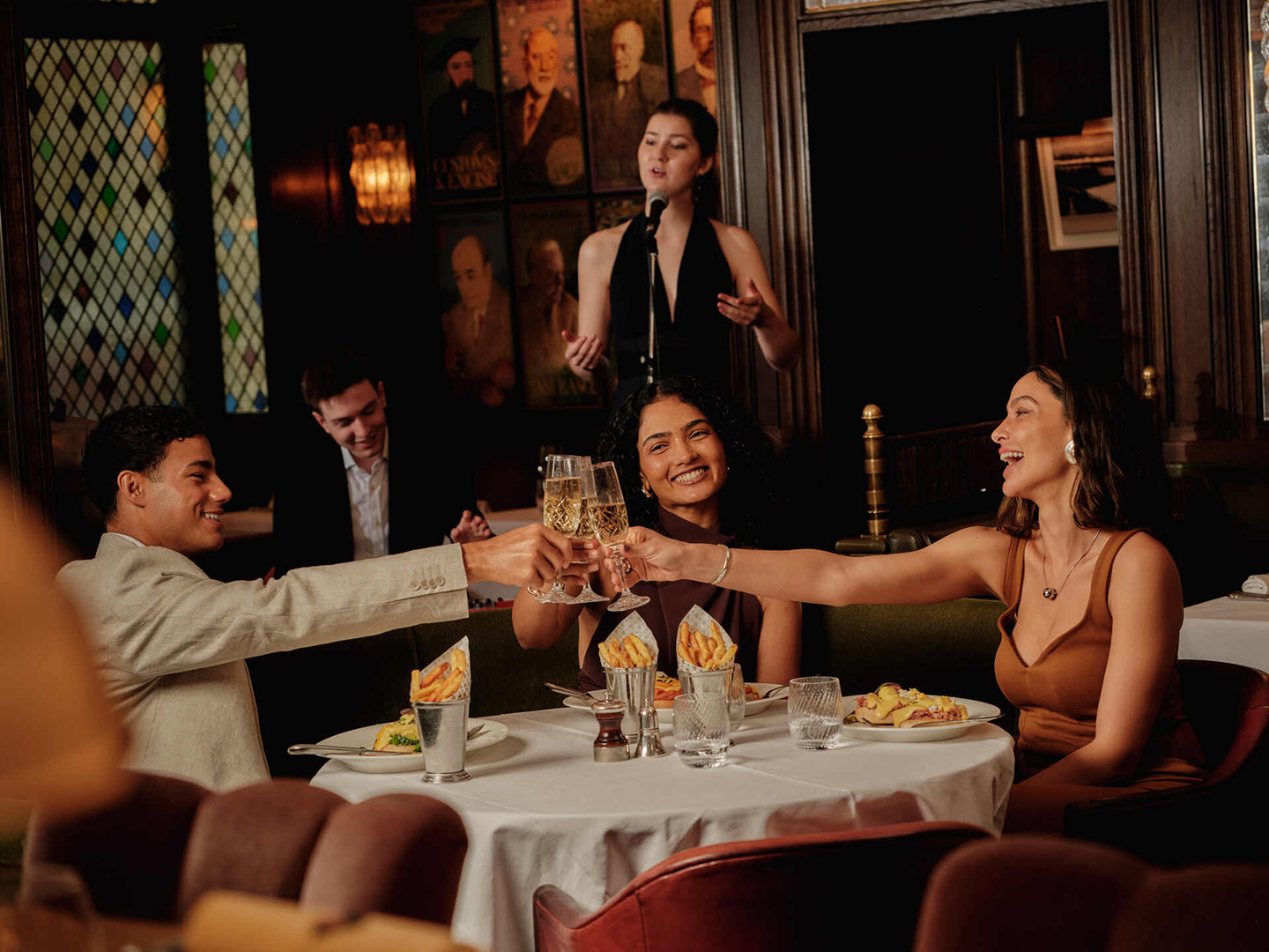 Guests toasting at a dinner during Ivy Live Music Fridays while a singer performs.