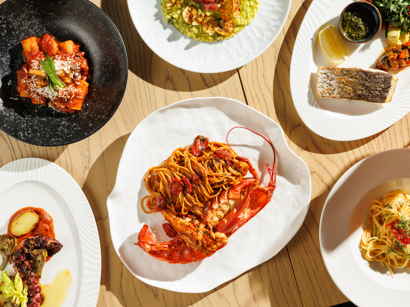 Assorted plated pasta and seafood dishes arranged for a shared restaurant meal.