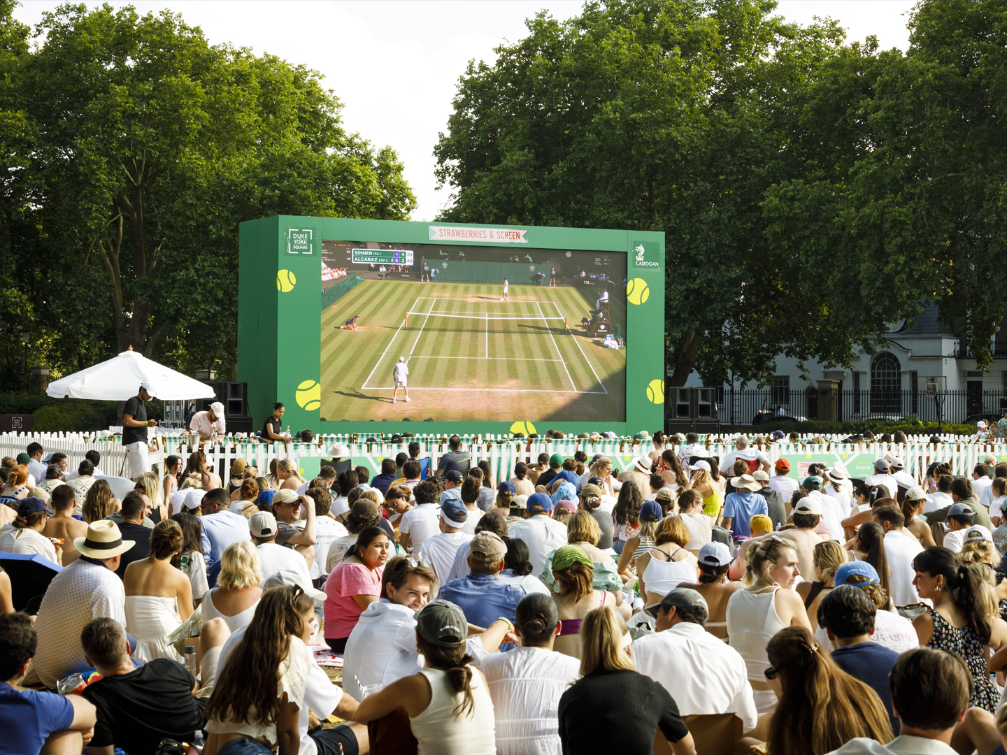 Outdoor public screening of a tennis match for a large seated audience