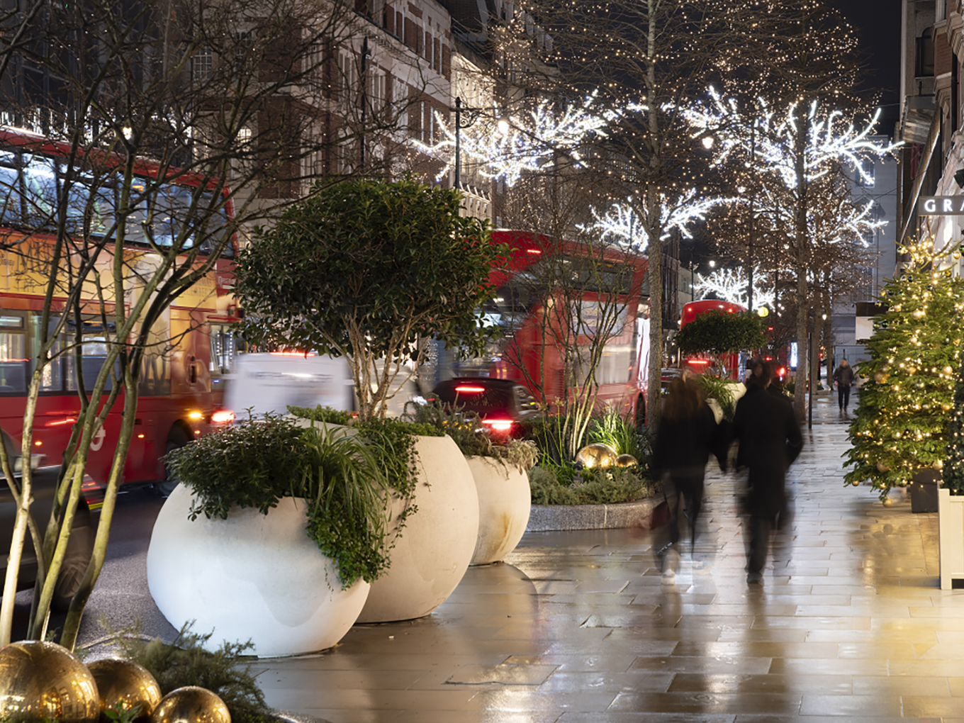 Sloane Street lined with illuminated Christmas trees and festive decorations welcoming evening shoppers.