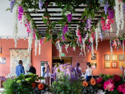 Treasure House Fair community market with hanging floral installations and visitors socializing.