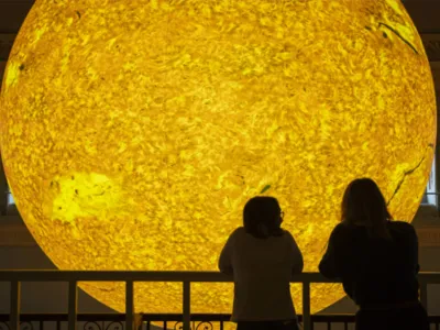 Visitors viewing a large illuminated model of the Sun in a museum exhibition
