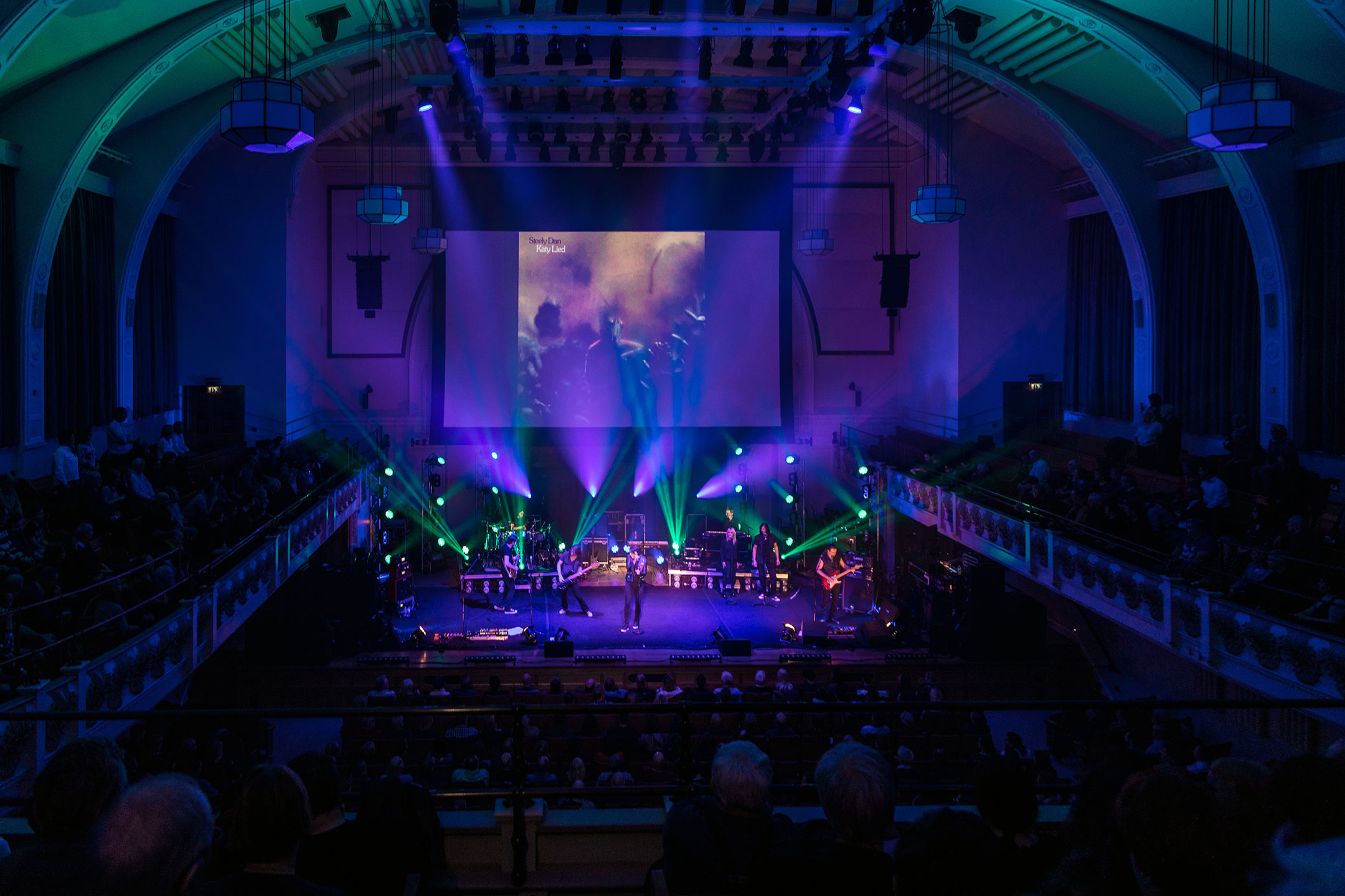 Live concert in a historic theater with a band onstage and an audience