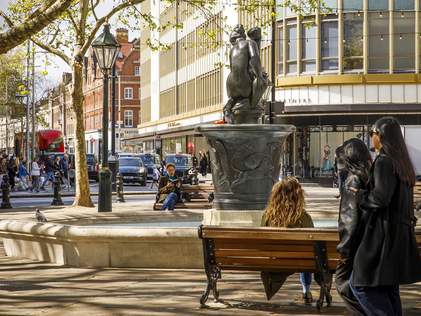 Sloane Square as a calm urban gathering place where people rest, socialize, and pass through.
