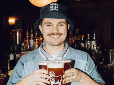 Bartender offering pints at a Chelsea pub where fans can watch World Cup matches.