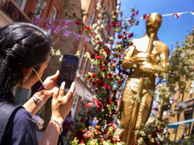 Person photographing a floral-decorated public art installation on a Chelsea street.